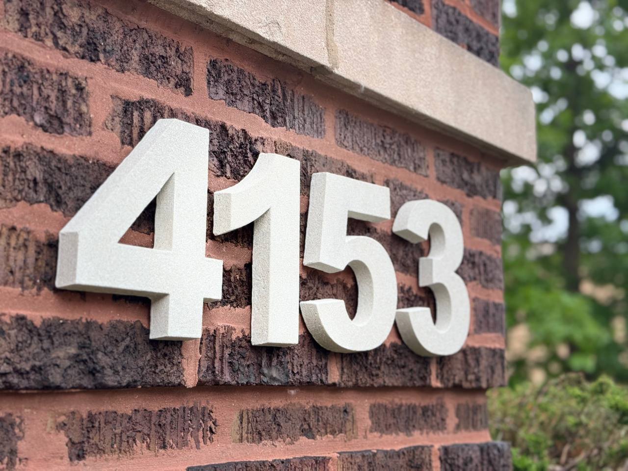 Warm Sandstone raised GFRC numbers installed on red brick